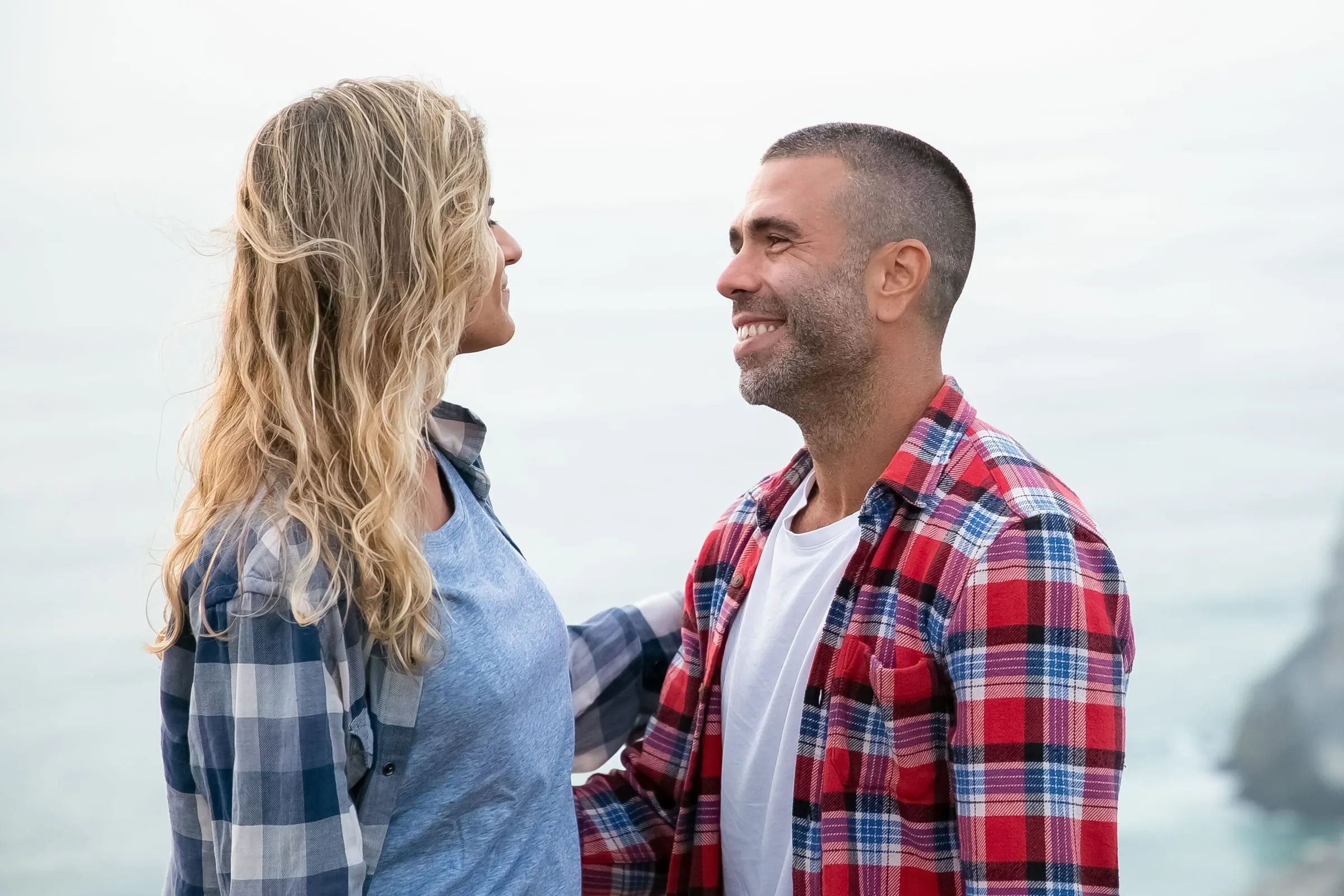 Smiling man and woman facing each other outdoors