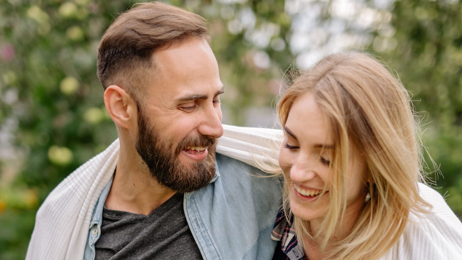 Laughing man and woman outdoors with a blanket around their shoulders